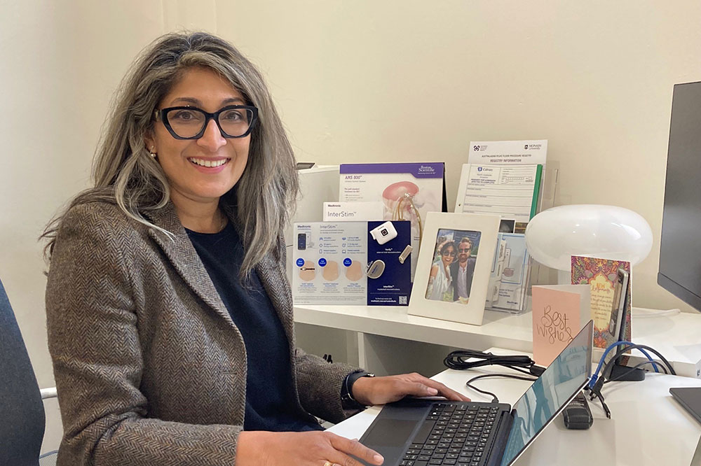 Dr Ashani Couchman smiling at the camera, sitting at an office desk.