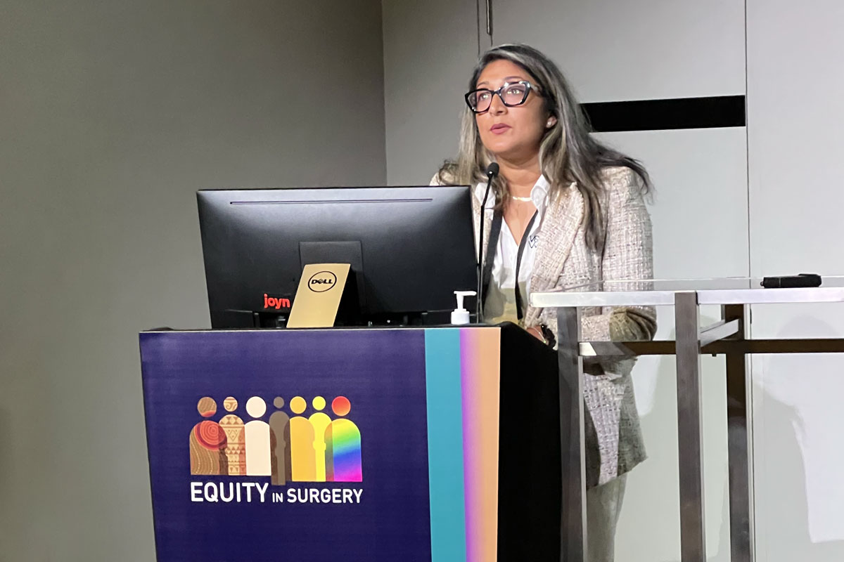 Dr Ashani Couchman presenting at a lectern (placard reads "Equity in Surgery").